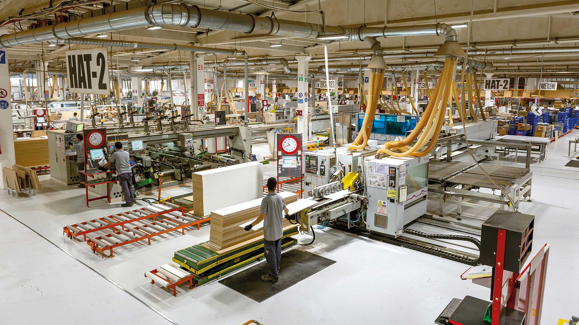 Produktionshal på Çileks fabrik med CNC-maskiner og medarbejdere ved kantlimerne